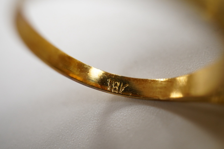 A gold and coral ring, 1970s, of textured design, set with a coral cabochon, mounted in gold, size N1/2, stamped 18K, gross weight approximately 7 grams